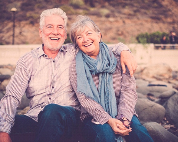 A smiling couple with dentures in Pacoima, CA by a lake
