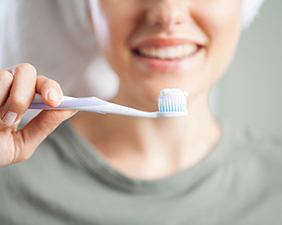 Woman with towel on head holding toothbrush