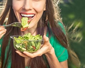 Woman in green shirt eating a salad