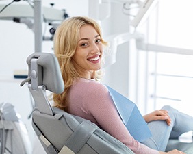 Blonde woman sitting in dental chair and smiling