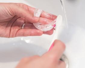 A hand holding an Invisalign aligner over an Invisalign case