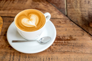 Latte sitting on wood table with heart shaped foam art